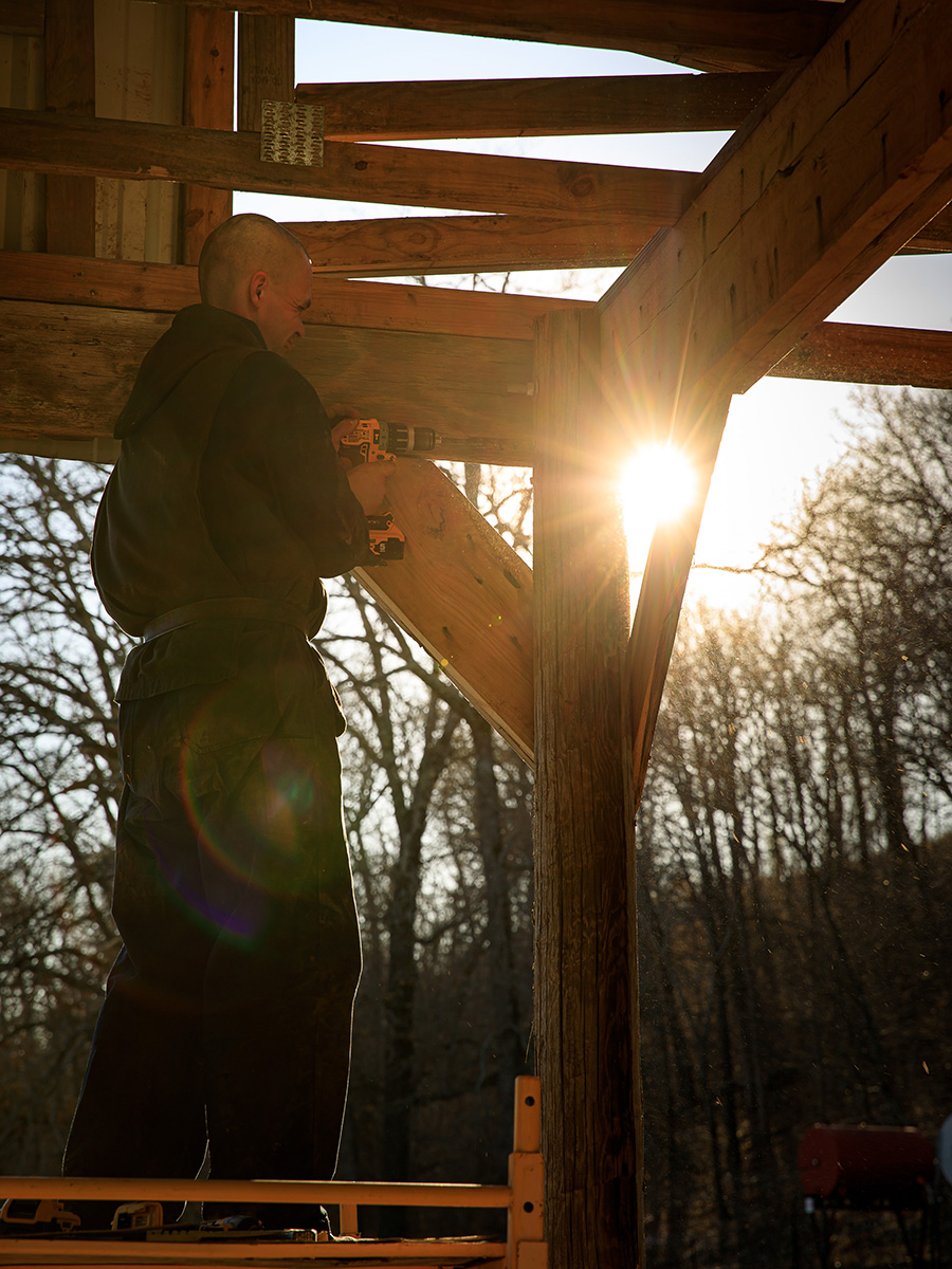 Monk working on a barn at sunset